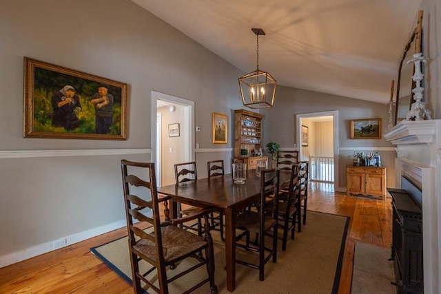 dining space featuring lofted ceiling, baseboards, and light wood-style floors