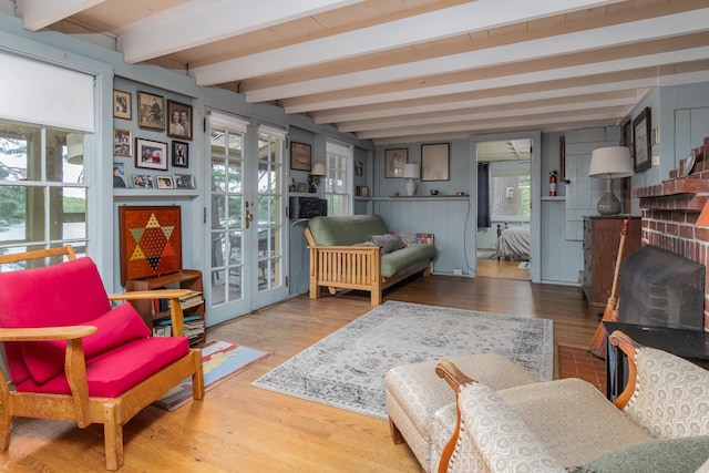 living area with french doors, beamed ceiling, and wood finished floors