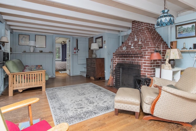 living room with beam ceiling, a fireplace, and wood finished floors