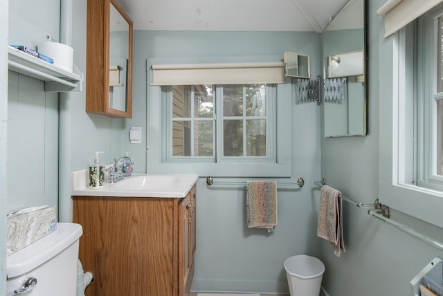 half bathroom featuring toilet, vanity, and a healthy amount of sunlight