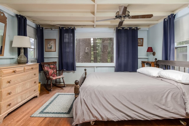 bedroom with multiple windows, beam ceiling, and wood finished floors