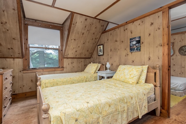 bedroom with wooden walls, vaulted ceiling, and wood finished floors