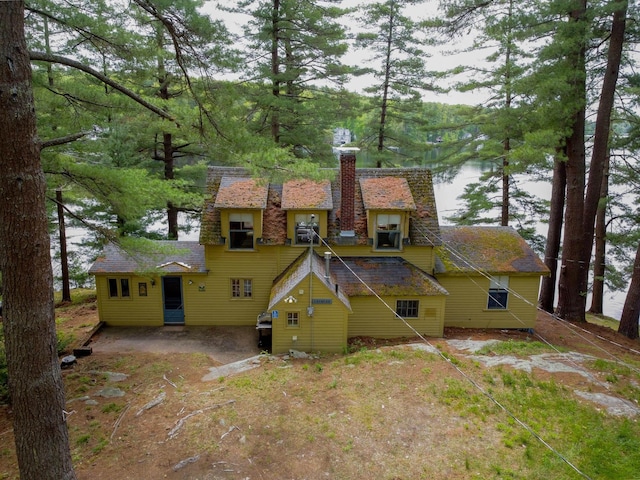 back of property with a water view and a chimney