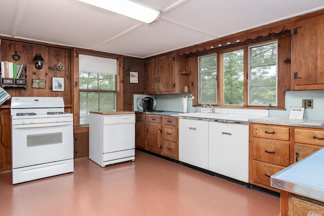 kitchen featuring brown cabinetry, light countertops, white range with gas cooktop, and fridge