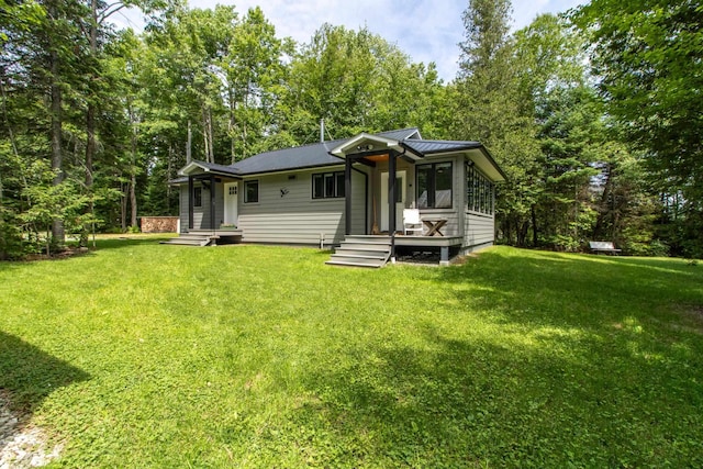 rear view of house featuring metal roof, a yard, and a standing seam roof