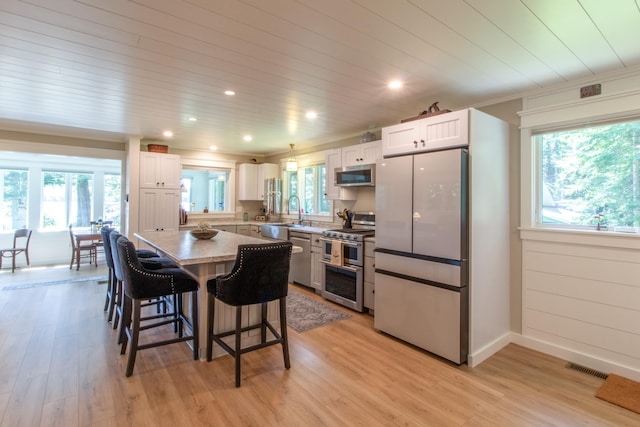 kitchen featuring stainless steel appliances, a breakfast bar area, a kitchen island, and white cabinetry