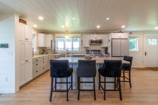 kitchen with a kitchen island, white cabinetry, appliances with stainless steel finishes, and a sink