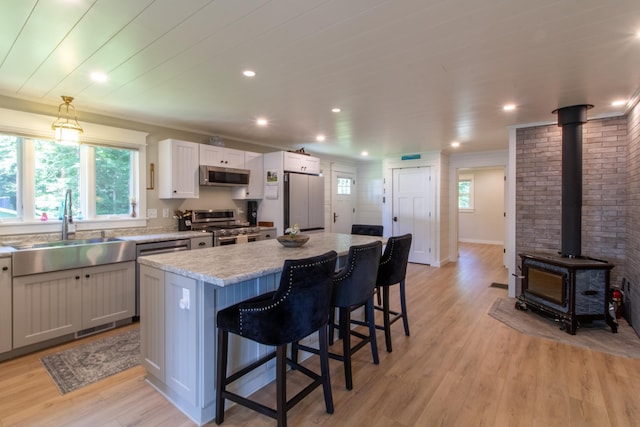 kitchen with a breakfast bar, pendant lighting, stainless steel appliances, a kitchen island, and a sink