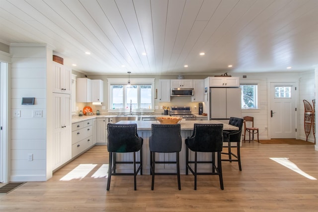 kitchen featuring a kitchen breakfast bar, stainless steel appliances, white cabinetry, and a center island