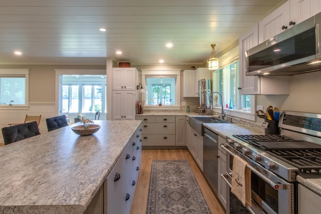 kitchen with a center island, stainless steel appliances, white cabinetry, a sink, and a kitchen breakfast bar