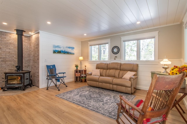 living area featuring ornamental molding, recessed lighting, a wood stove, and light wood-style flooring