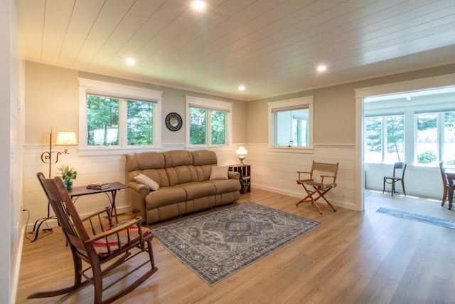 living room featuring light wood-type flooring, wood ceiling, and wainscoting