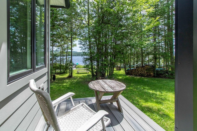 wooden deck featuring a water view and a lawn