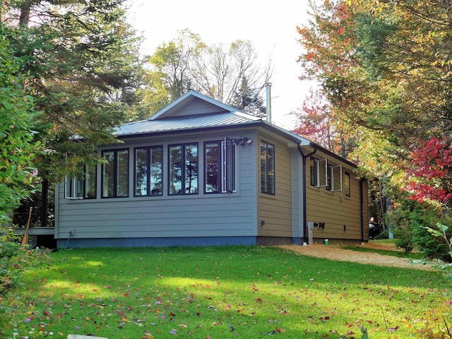 view of side of property with a sunroom, metal roof, and a lawn