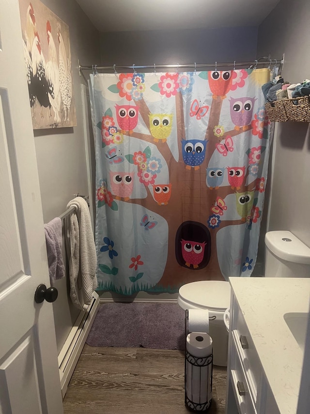 bathroom with a baseboard radiator, toilet, vanity, wood finished floors, and a shower with curtain