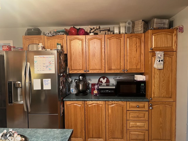 kitchen with black microwave, dark countertops, brown cabinets, and stainless steel fridge with ice dispenser