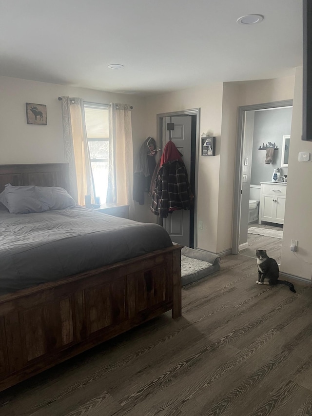 bedroom featuring connected bathroom, dark wood finished floors, and baseboards