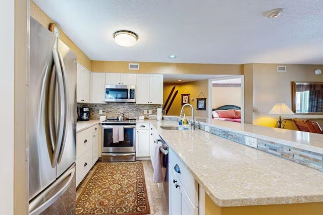 kitchen featuring appliances with stainless steel finishes, a sink, visible vents, and white cabinets