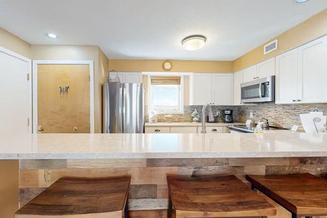 kitchen with light countertops, appliances with stainless steel finishes, and a kitchen bar