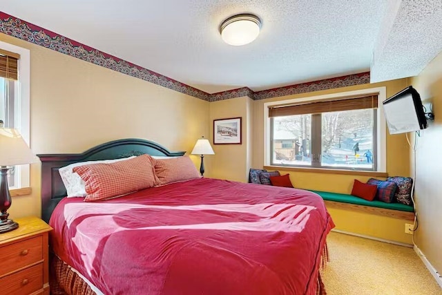 carpeted bedroom featuring a textured ceiling and baseboards