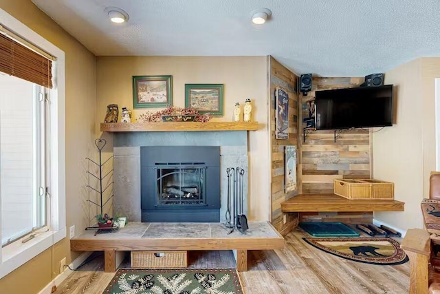 living room featuring a textured ceiling, a fireplace, and wood finished floors