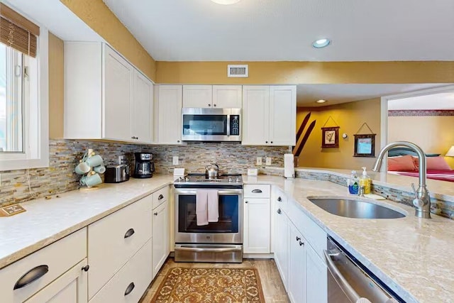 kitchen featuring appliances with stainless steel finishes, white cabinetry, a sink, and visible vents