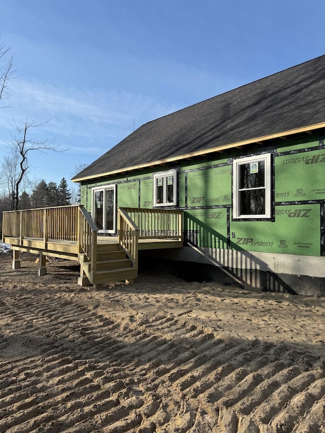 view of front of home featuring a wooden deck and a shingled roof