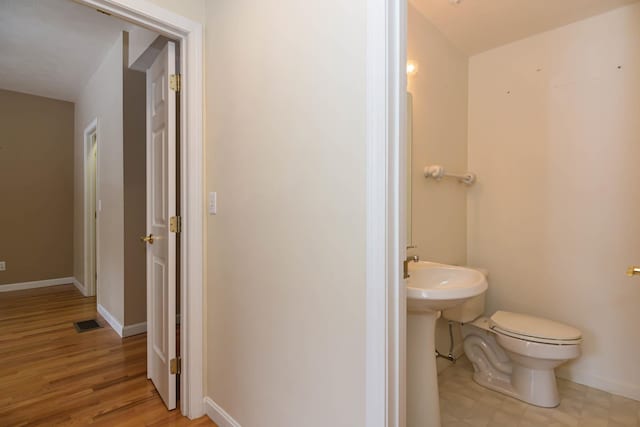 half bath featuring toilet, baseboards, visible vents, and wood finished floors