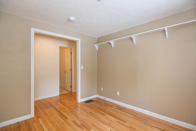 empty room with light wood-style floors, baseboards, and visible vents