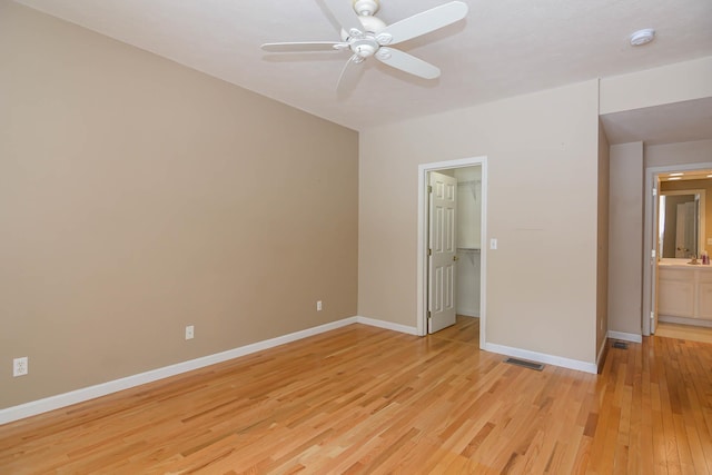 unfurnished bedroom with a walk in closet, light wood finished floors, a closet, a ceiling fan, and baseboards