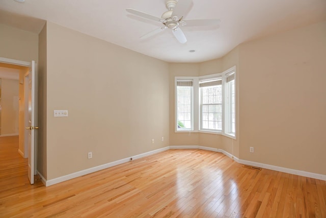 unfurnished room with light wood-type flooring, ceiling fan, visible vents, and baseboards