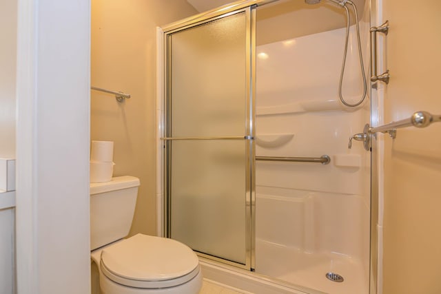 full bathroom featuring toilet and a shower with shower door