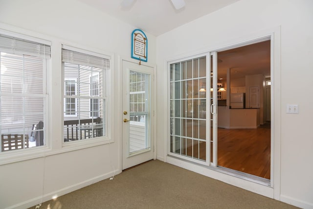 doorway with ceiling fan, baseboards, and carpet flooring