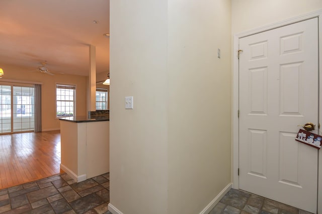 entryway featuring baseboards, ceiling fan, and stone tile floors