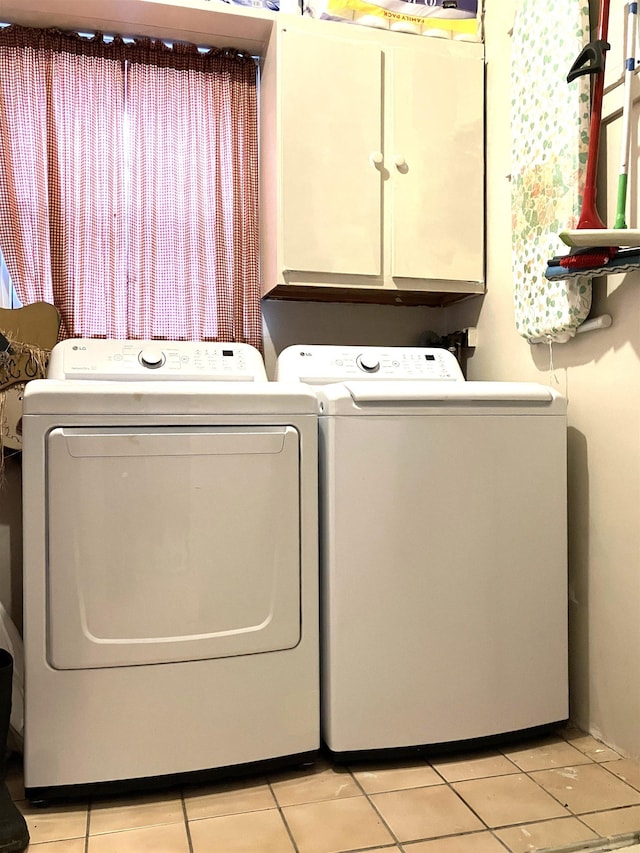 laundry room featuring washing machine and dryer, cabinet space, and light tile patterned floors