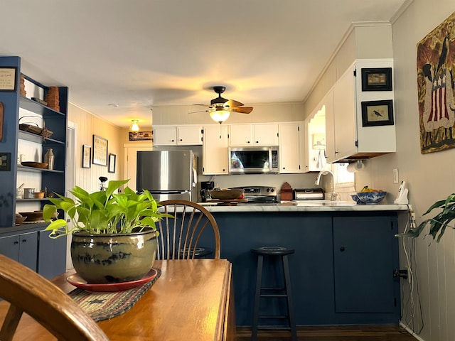 kitchen featuring crown molding, stainless steel appliances, a ceiling fan, white cabinets, and a sink