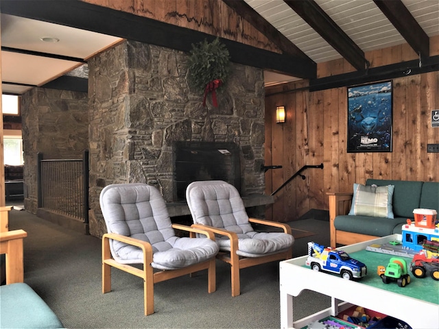 living area with vaulted ceiling with beams, wood walls, a fireplace, and carpet flooring