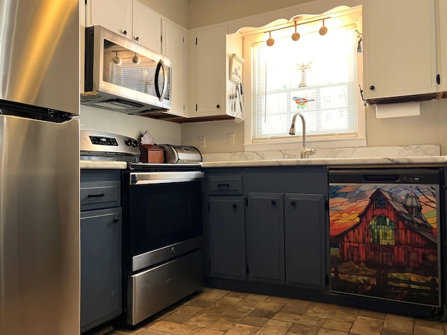 kitchen featuring stainless steel appliances, light countertops, gray cabinetry, white cabinets, and a sink