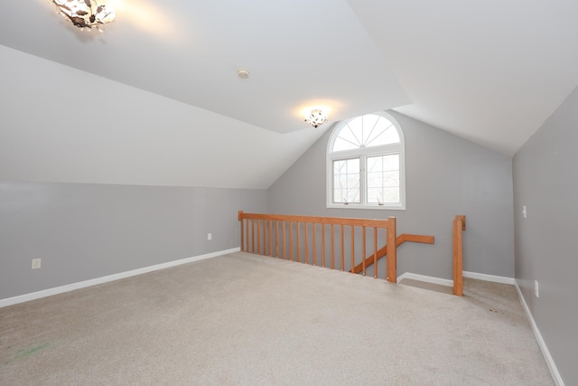 bonus room featuring vaulted ceiling, light carpet, and baseboards