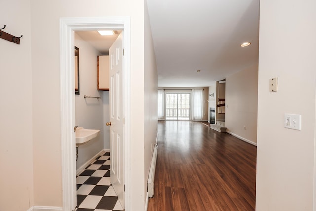 corridor with a baseboard radiator, baseboards, and tile patterned floors