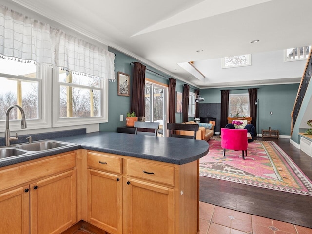 kitchen featuring dark countertops, open floor plan, tile patterned floors, a peninsula, and a sink