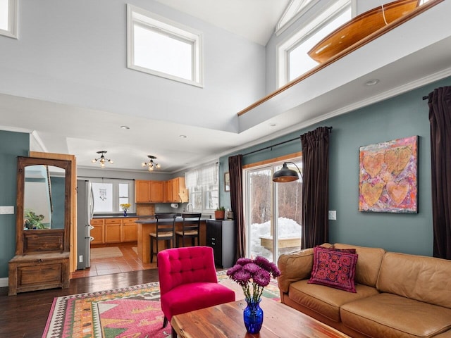 living room featuring a towering ceiling, ornamental molding, and wood finished floors