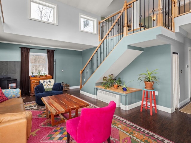 living area featuring stairs, wood finished floors, a towering ceiling, and baseboards