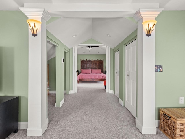 hallway featuring carpet floors, vaulted ceiling, decorative columns, and baseboards