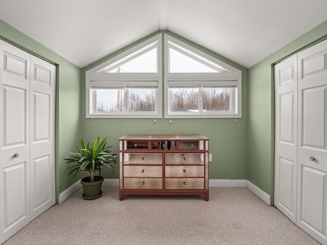 bedroom with lofted ceiling, a closet, light carpet, and baseboards