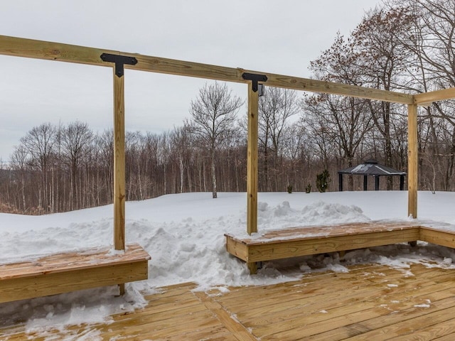 yard covered in snow with a wooden deck and a wooded view