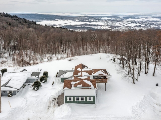 snowy aerial view featuring a wooded view