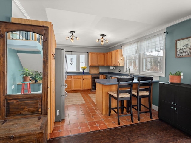 kitchen featuring wine cooler, dark countertops, freestanding refrigerator, a sink, and a peninsula