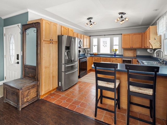 kitchen featuring dark countertops, appliances with stainless steel finishes, ornamental molding, a sink, and a peninsula