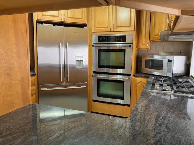 kitchen with stainless steel appliances, dark stone countertops, and tasteful backsplash